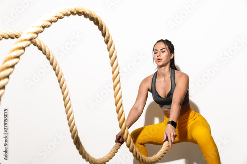 Concentrated amazing young sports fitness woman isolated over white wall background make exercises with ropes.