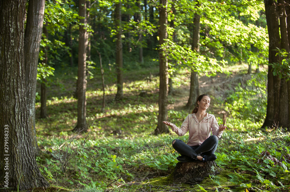 Beautiful woman meditating in the forest on a sunny morning Beautiful woman meditating in the forest on a sunny morning