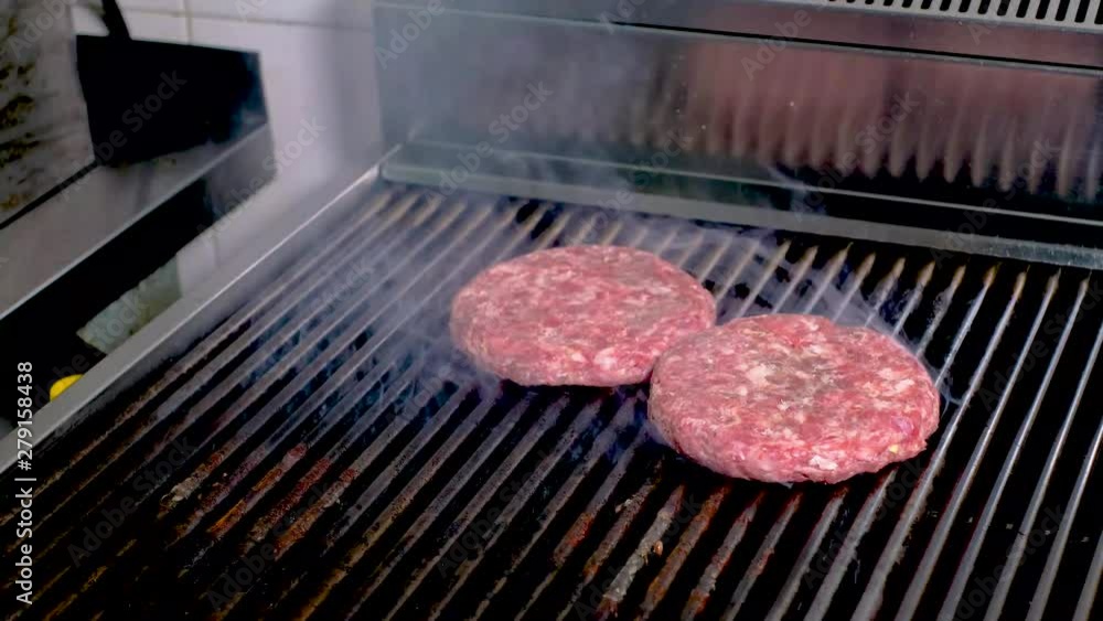grilled tomatoes and meat patty for a burger. the hands of the cook take the finished products grilled tomatoes and meat patty for a burger. the hands of the cook take the finished products