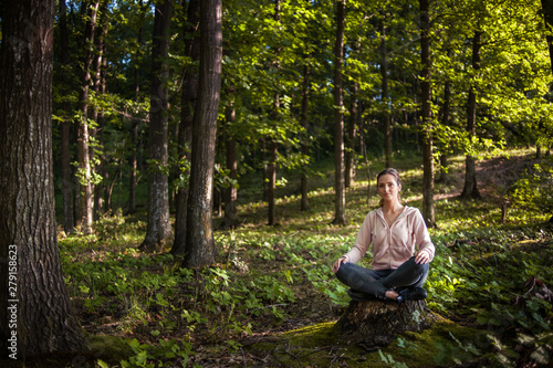 Beautiful woman meditating in the forest on a sunny morning © xpabli