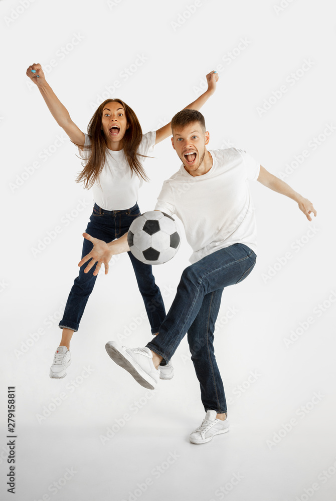 Fototapeta premium Beautiful young couple's portrait isolated on white studio background. Facial expression, human emotions, advertising, betting, sport concept. Man and woman playing football or soccer in action.