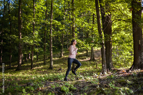 Young girl jogging in the woods on a sunny morning.