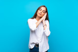 Young woman over isolated blue background making sleep gesture in dorable expression