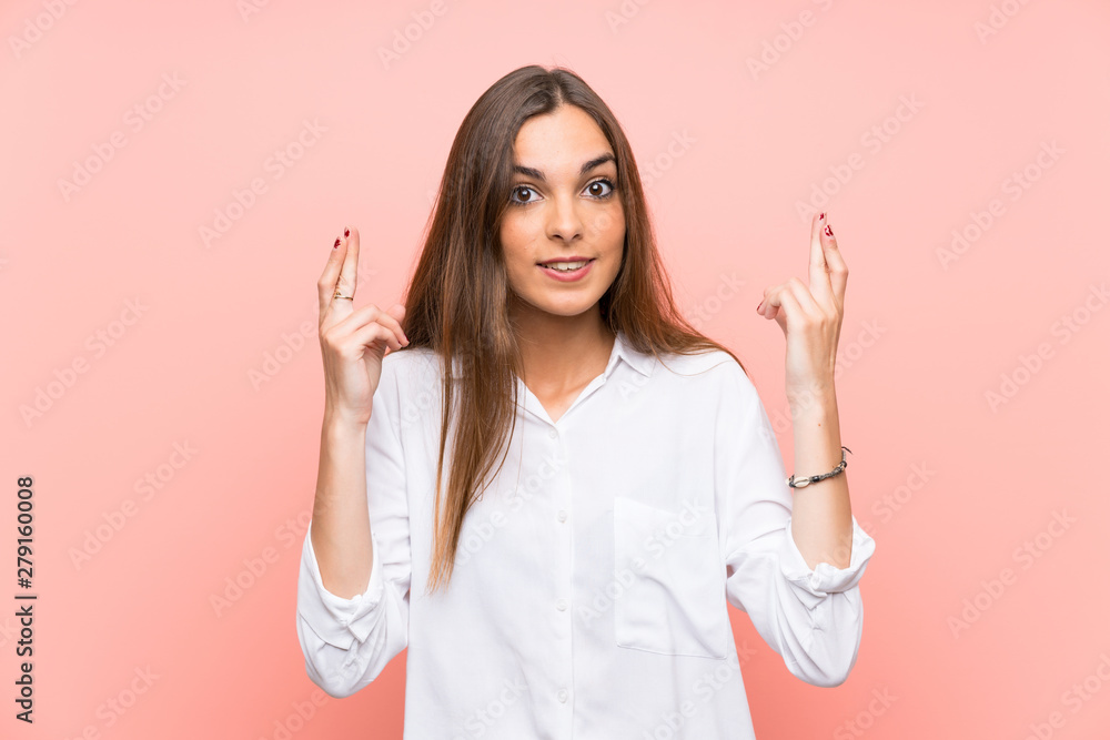 Young woman over isolated pink background with fingers crossing Young woman over isolated pink background with fingers crossing