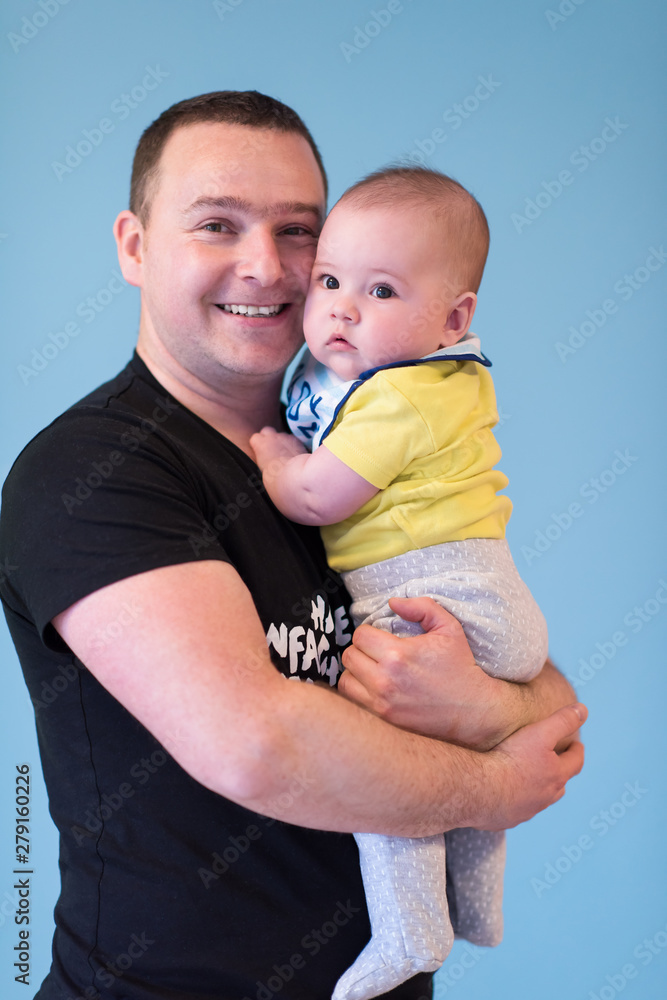 portrait of happy young father holding baby isolated on blue
