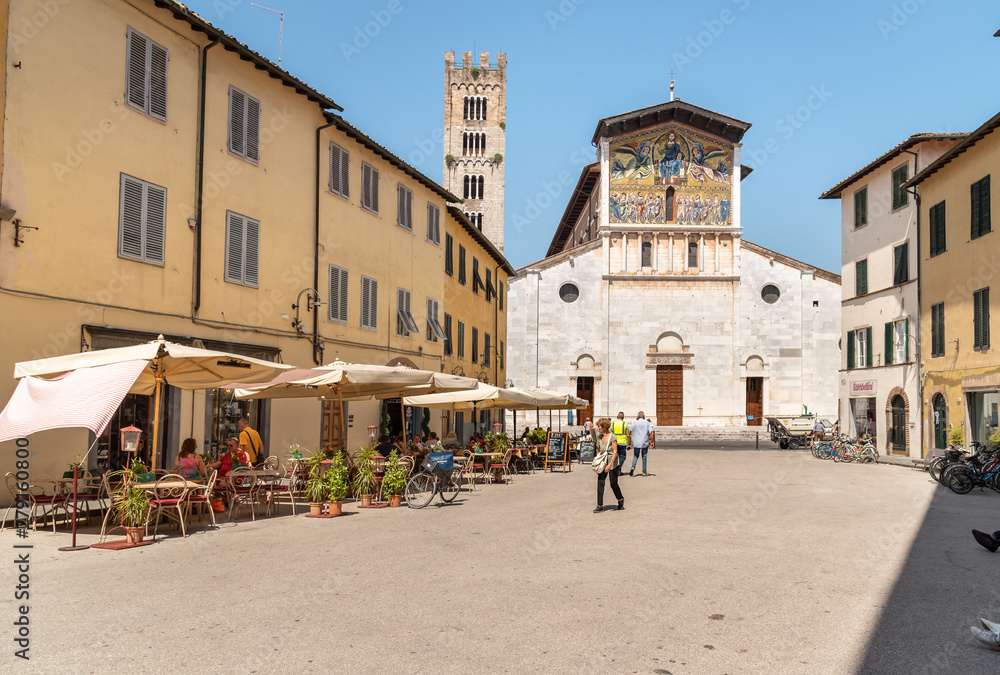 San Frediano square with people enjoying the outdoor bar and views of the Basilica of San Frediano in old town Lucca, Tuscany, Italy