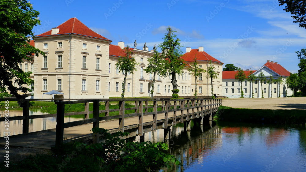 romantische Holzbrücke führt über Wasser zum Vordereingang von Schloss Rheinsberg in Brandenburg