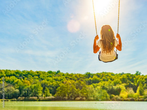Frau auf einer Schaukel an einem See mit Sandstrand