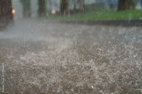 Raining day in the city at summer time. Texture of strong, fresh and powerful water drops and sprays. Puddle with ripple on Mocow road. Power, energy in nature