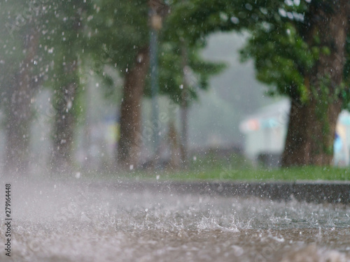Raining day in the city at summer time. Texture of strong, fresh and powerful water drops and sprays. Puddle with ripple on Mocow road. Power, energy in nature