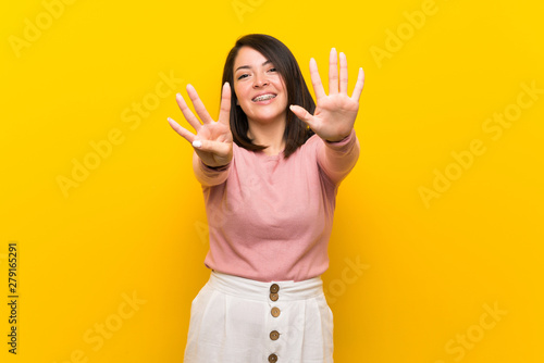 Young Mexican woman over isolated yellow background counting nine with fingers