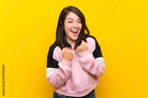 Young Mexican woman over isolated yellow background celebrating a victory