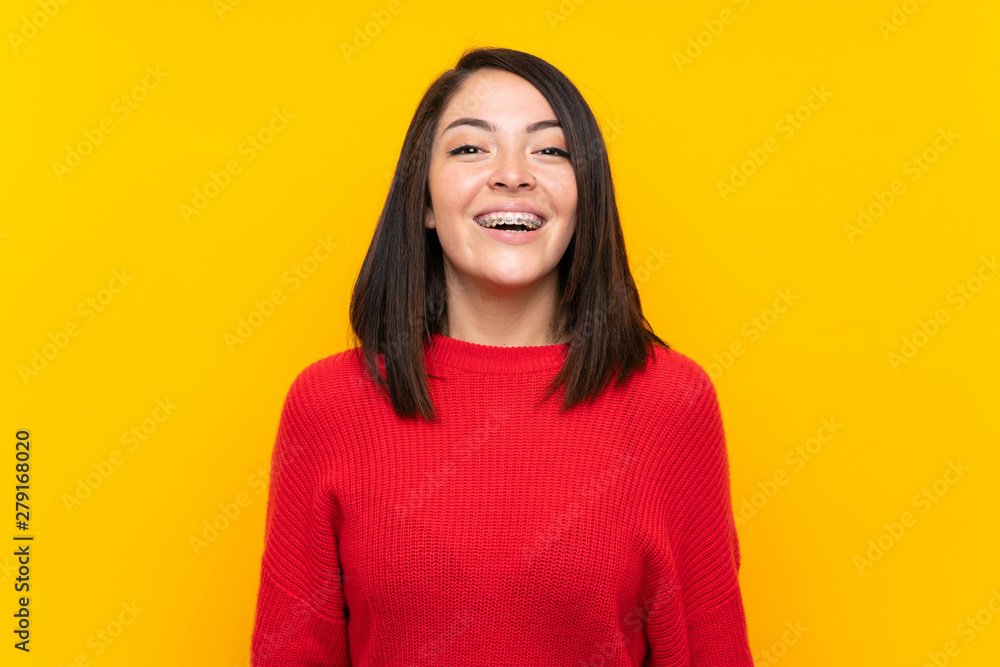 Young Mexican woman with red sweater over yellow wall with surprise facial expression Young Mexican woman with red sweater over yellow wall with surprise facial expression
