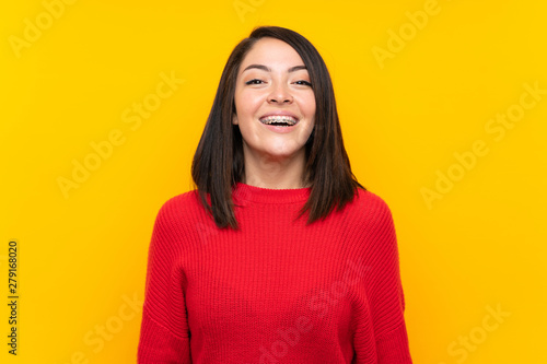 Young Mexican woman with red sweater over yellow wall with surprise facial expression © luismolinero