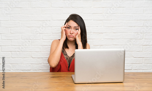 Young Mexican woman with a laptop unhappy and frustrated with something. Negative facial expression