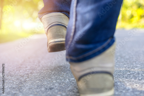 Man in jeans and sport sneakers walking on road. Focus on sneakers. With copy space for text or desing