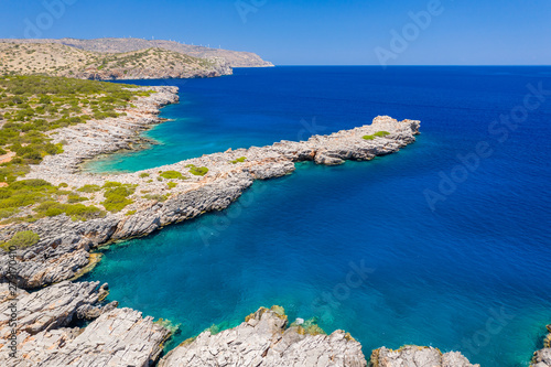 Aerial view of a clear, deep blue ocean and dry, yellow summer coastline (Kolokitha Island, Greece)