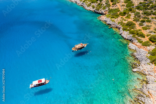 Aerial drone view of boats and swimmers in a crystal clear, blue, warm ocean