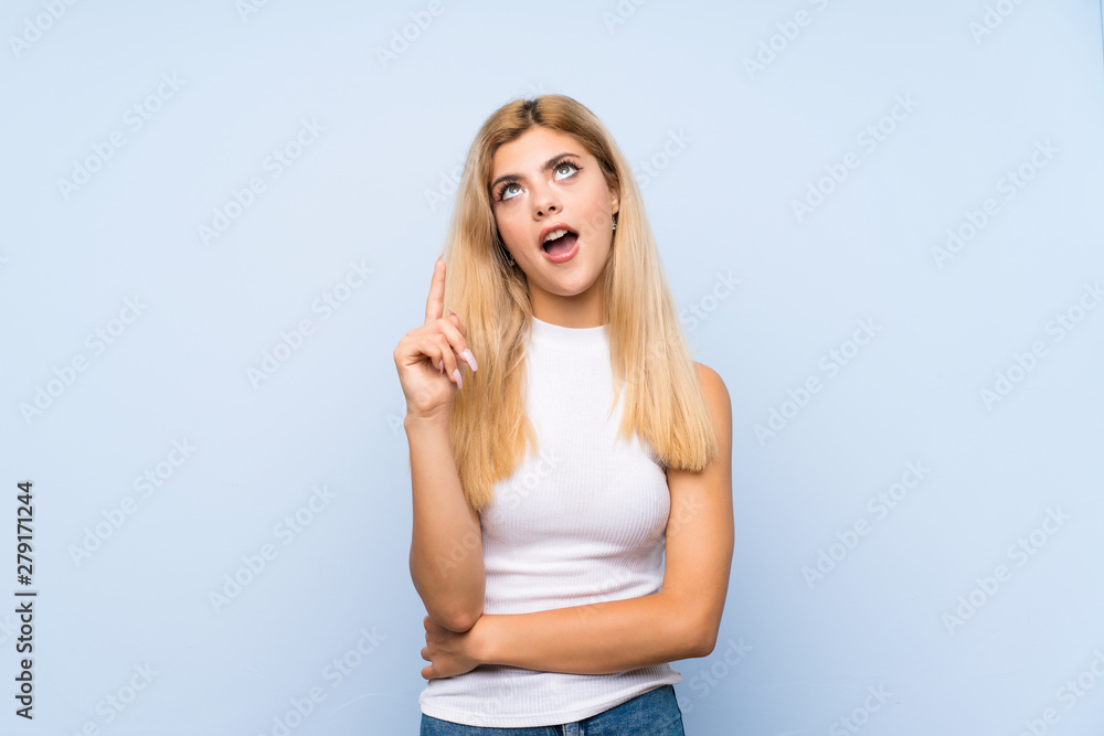 Teenager girl over isolated blue background pointing back Teenager girl over isolated blue background pointing back