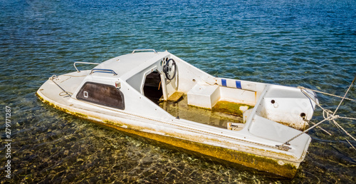 Half sunk abandoned white boat  floating on the water