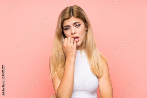 Teenager girl over isolated pink background nervous and scared