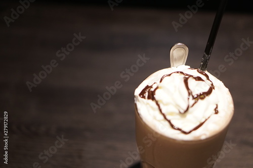 Chocolate frappe with whipped cream on a wooden table over blur background at cafe. photo