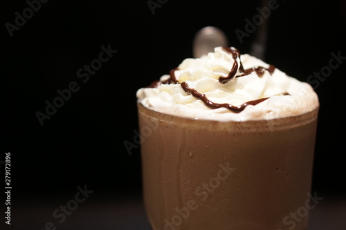 Chocolate frappe with whipped cream on a wooden table over blur background at cafe. photo