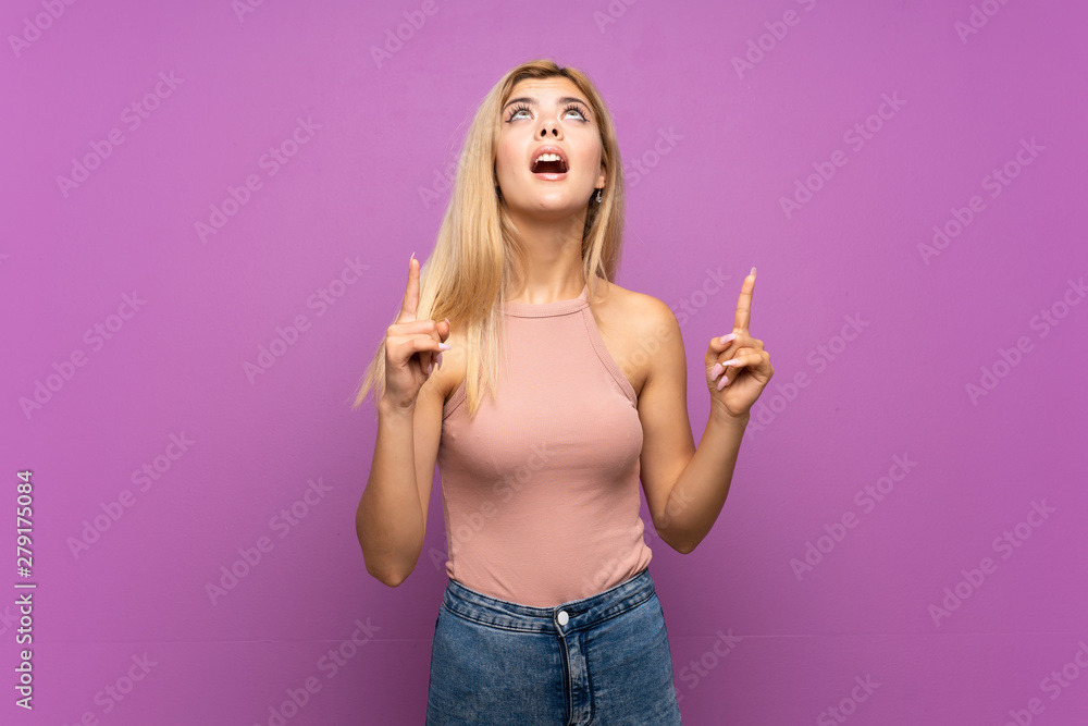 Teenager girl over isolated purple background surprised and pointing up Teenager girl over isolated purple background surprised and pointing up