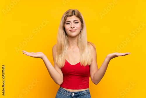 Teenager girl over isolated yellow background having doubts with confuse face expression