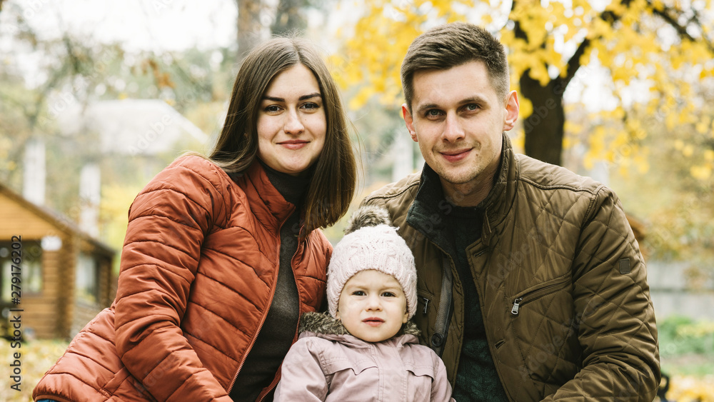 Parents and little daughter sitting in autumn park Parents and little daughter sitting in autumn park