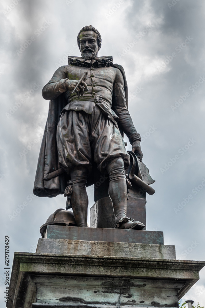 Bruges, Flanders, Belgium -  June 17, 2019: Closeup of Simon Stevin statue isolated against dark rainy cloudscape. 