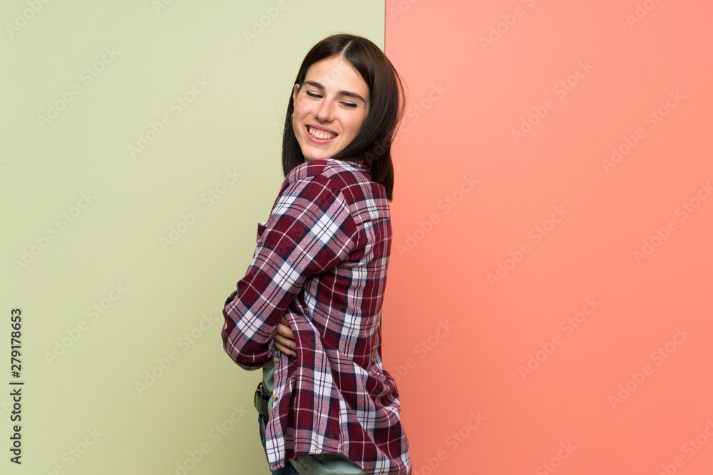 Obraz premium Young woman over isolated colorful wall with arms crossed and happy