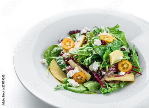 Healthy fresh salad with mix greens, apple, cream cheese, cranberry, sauce and edible flowers in plate on isolated white background. Healthy food, vegetarian dieting, close up