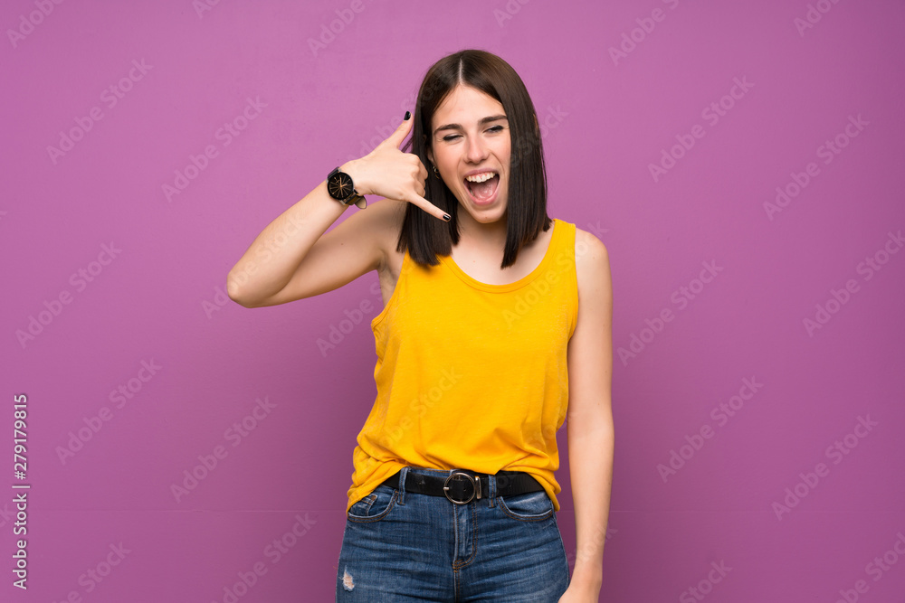 Young woman over isolated purple wall making phone gesture. Call me back sign Young woman over isolated purple wall making phone gesture. Call me back sign