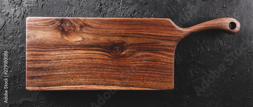 Chopping cutting board on dark stone background. Wooden texture. Top view, toning