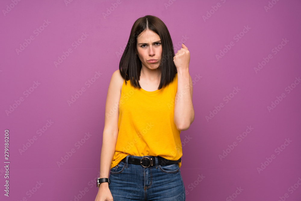 Young woman over isolated purple wall with angry gesture Young woman over isolated purple wall with angry gesture