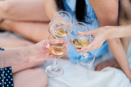Three female hands with glasses of white wine. Toast, congratulations on an outdoor picnic. The concept of relaxation and companionship.