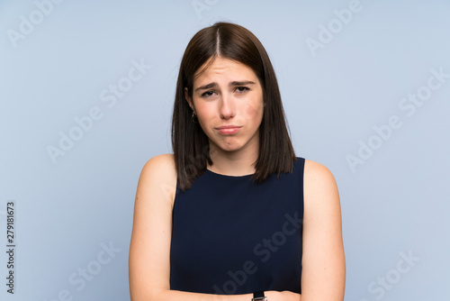 Young woman over isolated blue wall sad