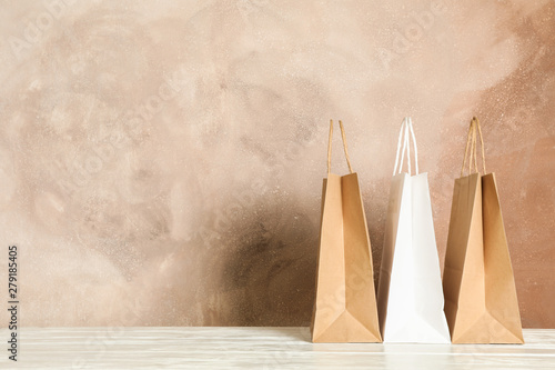 Paper bags on white table against brown background, copy space photo