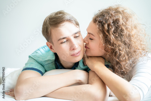 Funny loving couple lying on bed in morning