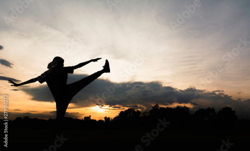 Silhouette of young woman practicing yoga outdoor. Female happiness. Sport and healthy concept.