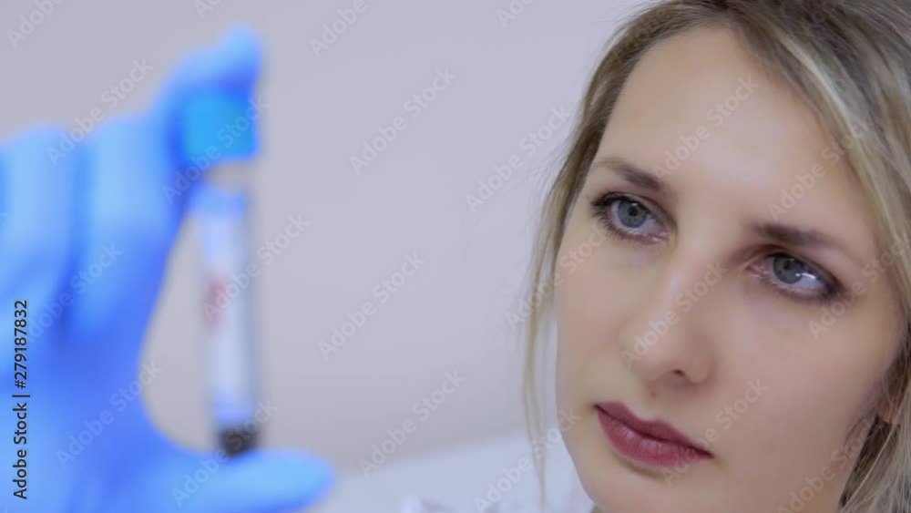 Working in medical laboratory at hospital making tests. Portrait of woman laboratory technician holding test tube in her hand in gloves. Working in medical laboratory at hospital making tests. Portrait of woman laboratory technician holding test tube in her hand in gloves.