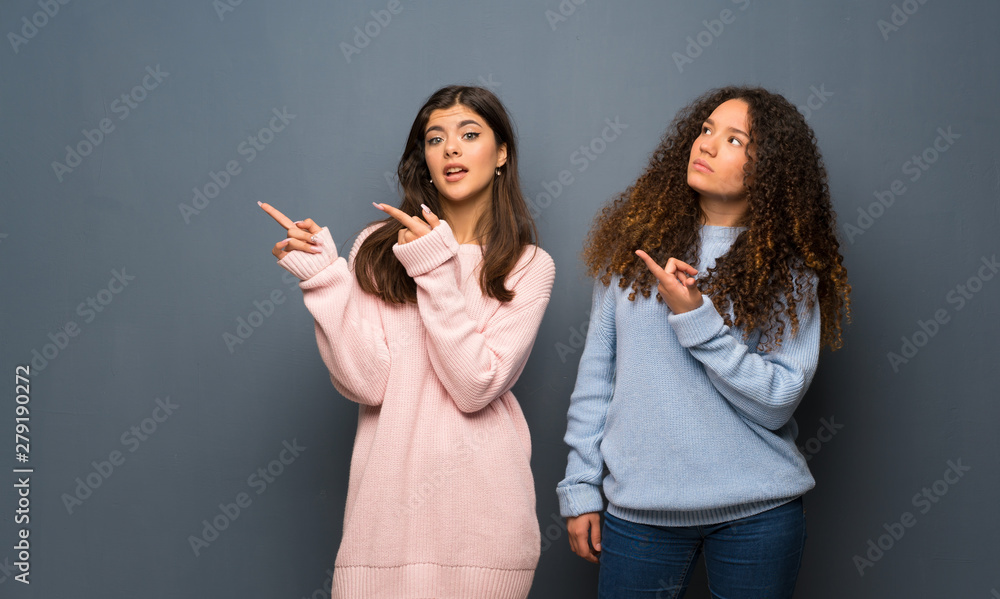 Teenager friends frightened and pointing to the side Teenager friends frightened and pointing to the side