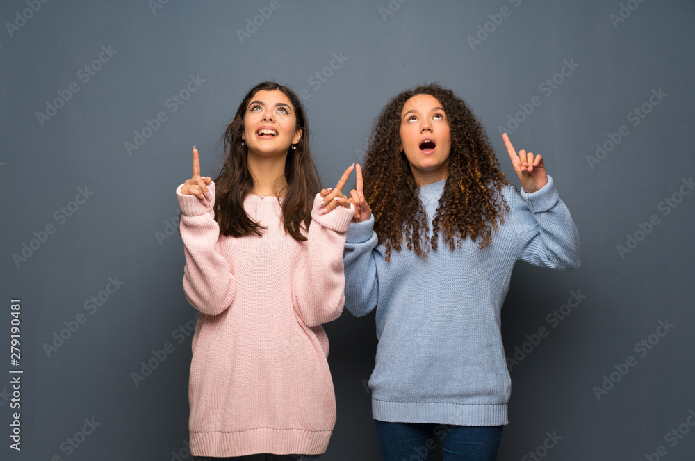 Teenager friends surprised and pointing up Teenager friends surprised and pointing up