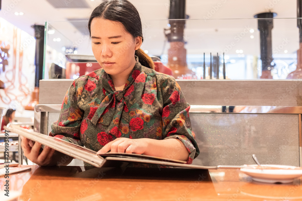 Bangkok, Thailand, Jul 14, 2019 - Asian woman looking at the menu before order food in Japanese restaurant Bangkok, Thailand, Jul 14, 2019 - Asian woman looking at the menu before order food in Japanese restaurant