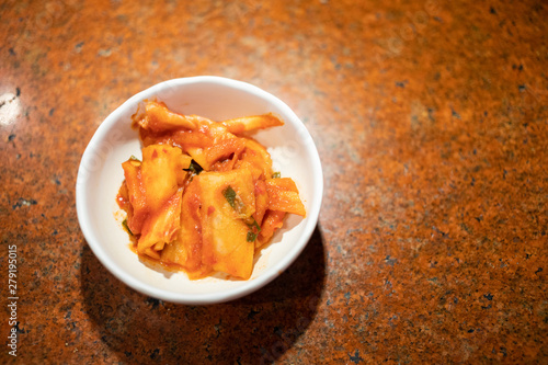 Kimchi in small white bowl on table, Traditional Korean food photo