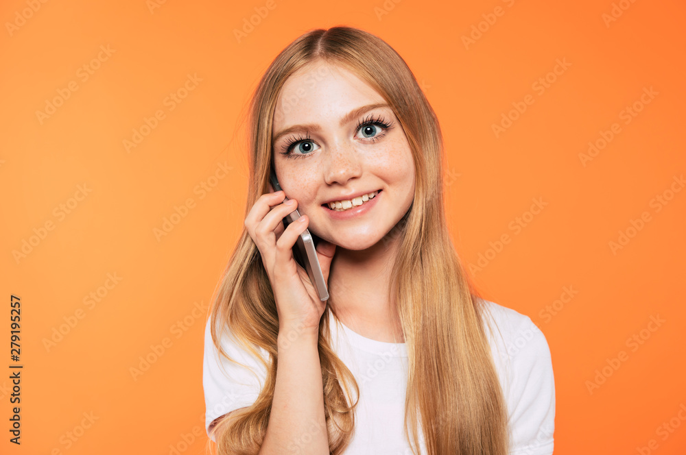 Happy attractive little blonde girl with smart phone isolated on yellow background Happy attractive little blonde girl with smart phone isolated on yellow background