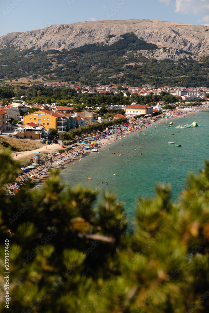 Adriatic Sea coastline in Croatia. Rocky shore with turquoise sea water. Baska island, touristic destination in Croatia. Mountains in the background. First plan in defocus.