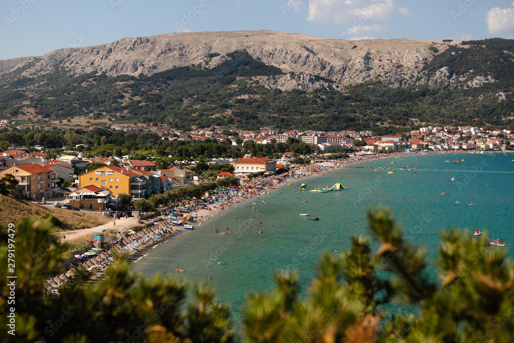 Adriatic Sea coastline in Croatia. Rocky shore with turquoise sea water. Baska island, touristic destination in Croatia. Mountains in the background. First plan in defocus.