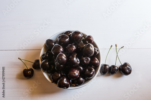 close of fresh organic summer ripe black cherries in a white porcelain bowl room for text  fileld frame  photo